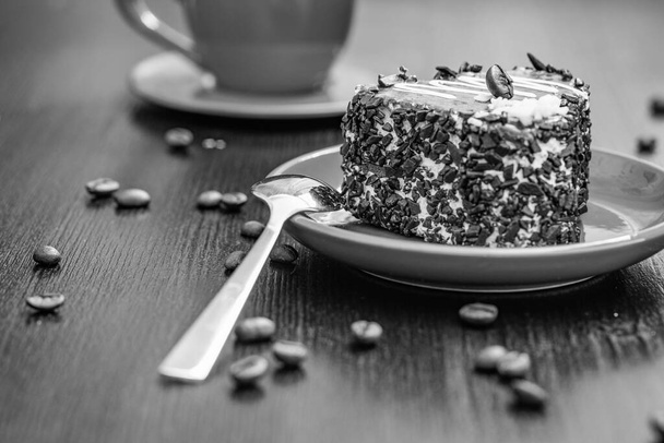 Вкусный пирог в форме сердца, посыпанный кусочками шоколада, лежит на красной тарелке. Фотография крупным планом на деревянном фоне. - Фото, изображение