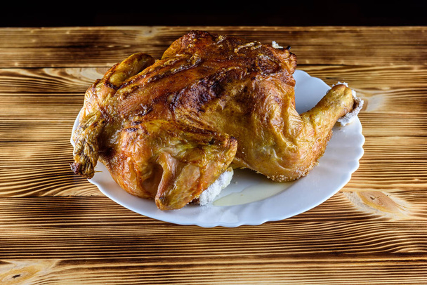 fried chicken whole, on a white plate on a wooden background - Zdjęcie, obraz