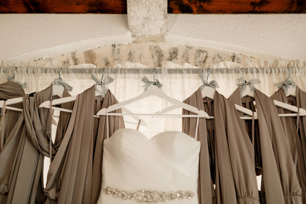Primo piano dell'abito da sposa delle spose sullo sfondo degli abiti da damigella d'onore sulla cornice. - Foto, immagini
