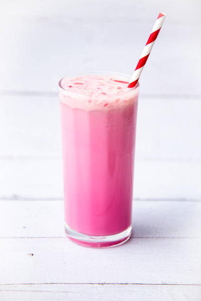 розовый клубничный молочный коктейль в высоких стаканах изолированы на белом деревянном фоне стола, Селективный фокус, Здоровое питание на завтрак и закуски. - Фото, изображение