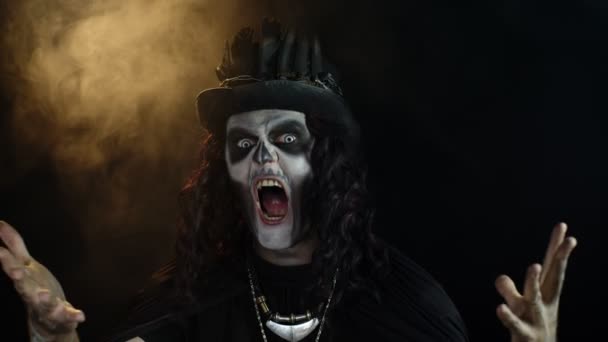 Frightening man in skeleton Halloween makeup screaming, shouting, making faces, trying to scare - Footage, Video