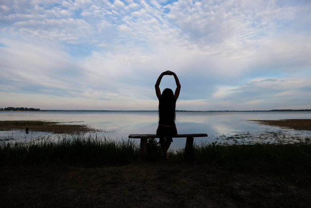 Sylwetka szczęśliwej kobiety na tle wschodu słońca. Jezioro Svitiaz, Shatsk National Park, Wołyń, Ukraina. - Zdjęcie, obraz