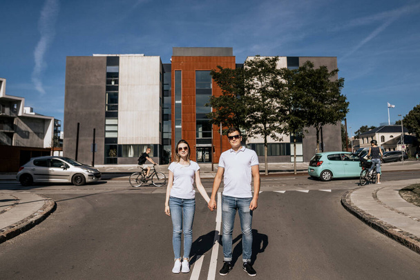 Стильная пара в белой футболке улыбается стоя на улице - Фото, изображение