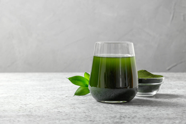 Chlorella healthy detox drink in glass and powder in bowl on a grey background. Close up. Space for design. - Fotoğraf, Görsel