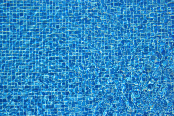 Vista superior del agua clara en un fondo azul de la piscina de azulejos. Efecto de ondulación. - Foto, Imagen