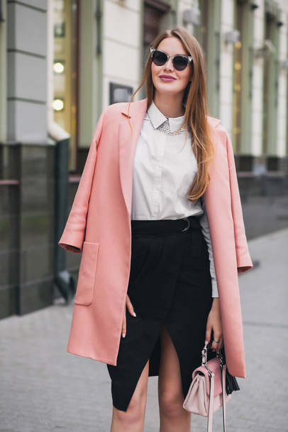 attractive stylish smiling rich woman walking city street in pink coat spring fashion trend holding purse, elegant style, wearing sunglasses - Foto, imagen