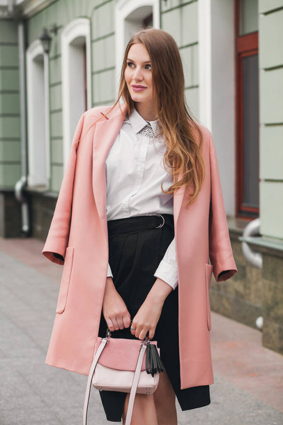young stylish beautiful woman walking in street, wearing pink coat, purse, white shirt, black skirt, fashion outfit, autumn trend, smiling happy, accessories - Foto, imagen