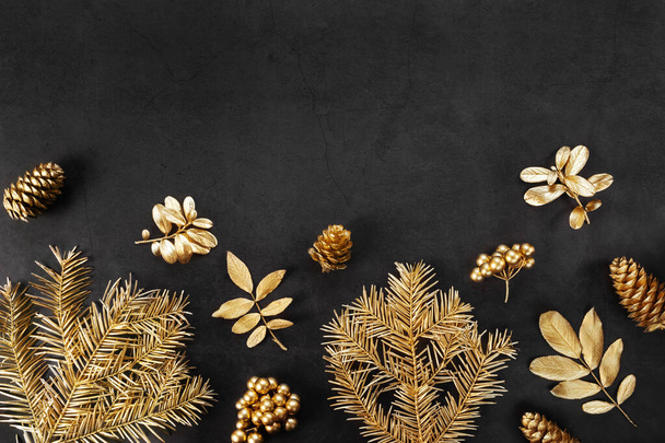 New Year's flat lay in golden and black shades. Spruce branches, leaves, cones and berries are painted with golden paint. Stylish concept of christmas, celebration. Top view, minimalism, copy space. - Photo, Image