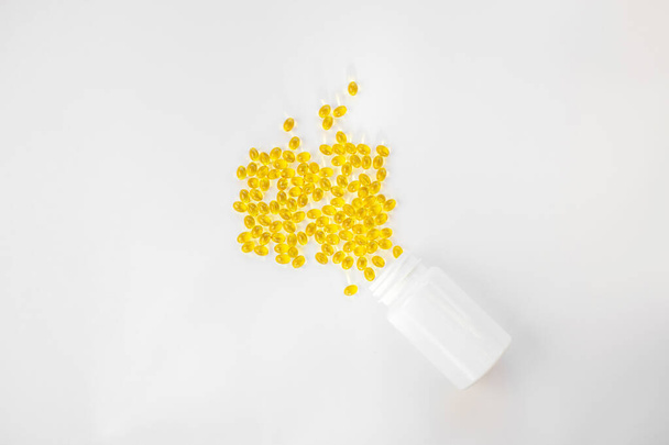 Concepto creativo vitamina D3, vitamina solar. Cápsulas en una botella blanca. Copiar espacio, minimalismo, vista superior. - Foto, Imagen