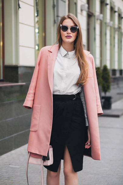 sexy young stylish beautiful woman walking in street, wearing pink coat, purse, sunglasses, white shirt, black skirt, fashion outfit, autumn trend, smiling happy, accessories - Fotó, kép