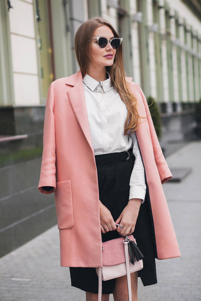 attractive stylish smiling rich woman walking city street in pink coat spring fashion trend holding purse, elegant style, wearing sunglasses - Foto, Imagem