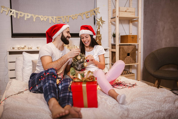 Mladý pár zdobí vánoční stromek doma - Fotografie, Obrázek