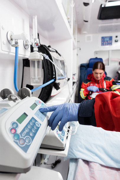 Selective focus of paramedic using equipment near colleague in ambulance car  - 写真・画像