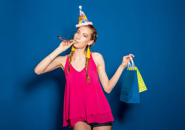 young hipster beautiful woman, colorful outfit, trend fashion style, blue background, holding shopping paper bags, presents, smiling, happy, celebrating birthday - Photo, image