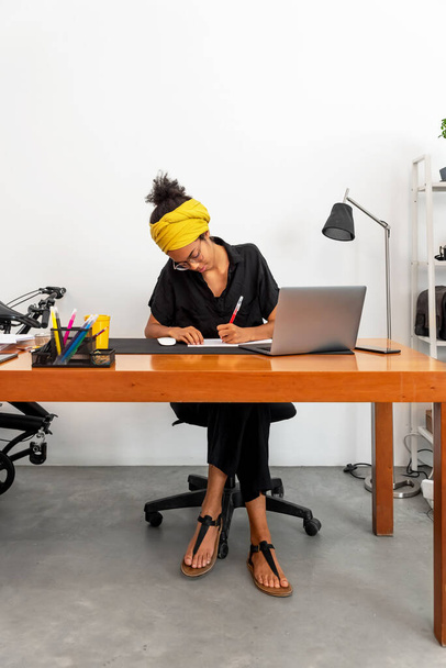 Snímek mladé latinské ženy pracující v domácí kanceláři s notebookem a dokumenty - Fotografie, Obrázek