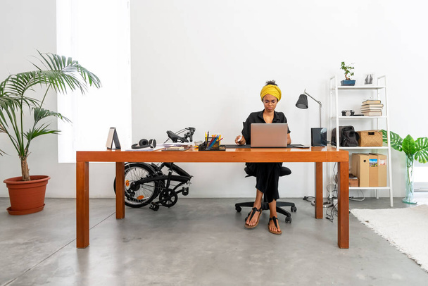 Tiro de jovem mulher latina trabalhando em casa escritório com laptop e documentos - Foto, Imagem