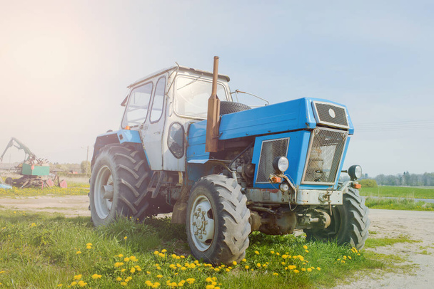 Stary niebieski ciągnik rolniczy zardzewiały i uszkodzony - Zdjęcie, obraz