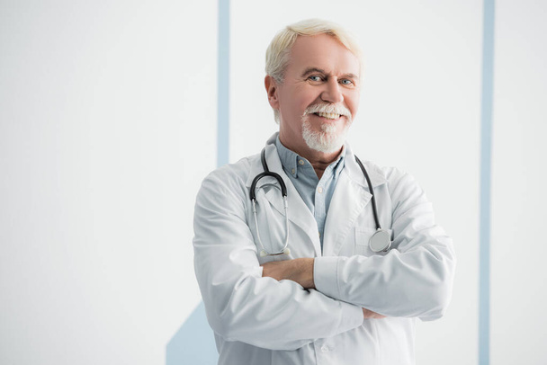 Elderly doctor with crossed arms looking at camera  - Foto, imagen