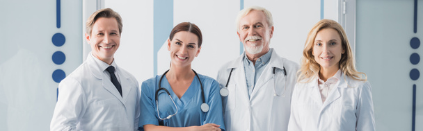 Панорамный снимок персонала больницы, смотрящего на камеру в клинике  - Фото, изображение