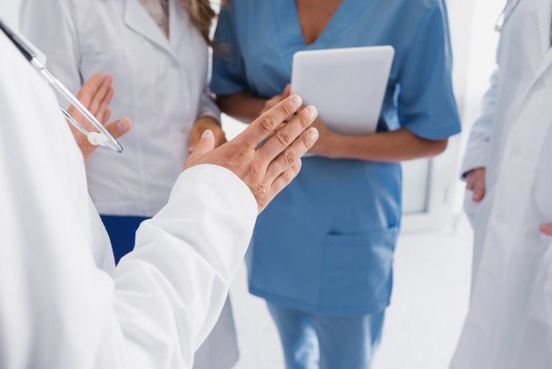 Gehakt zicht op arts in de buurt van collega 's en verpleegkundige met digitale tablet  - Foto, afbeelding