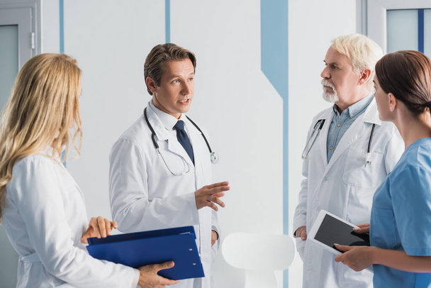 Concentration sélective du médecin parlant avec l'infirmière et ses collègues à la clinique  - Photo, image