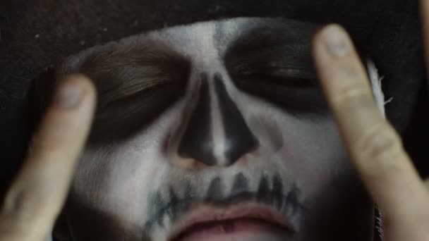 Primer plano hombre cara en esqueleto Halloween cosplay quitar las manos de la cara y mirando de par en par los ojos abiertos - Metraje, vídeo