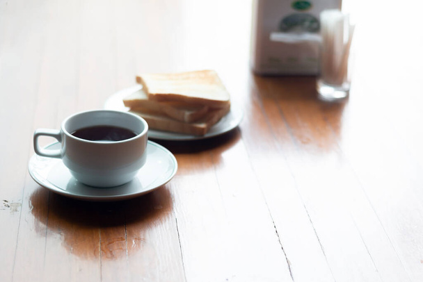 Eine Tasse Kaffee mit Toast auf einem Holztisch zum Frühstück. - Foto, Bild