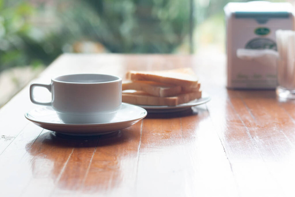 Egy csésze kávé pirítóssal a fa asztalon reggelire.. - Fotó, kép