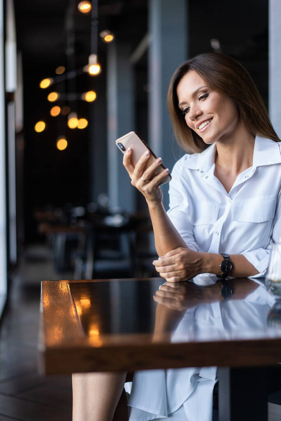 Young businesswoman using phone in coffee shop - Foto, afbeelding