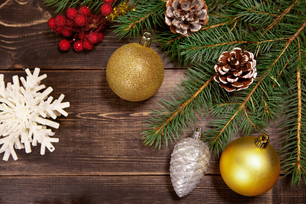 Рождественские игрушки с праздничными еловыми иглами на коричневом деревянном фоне. Новогодний фон - Фото, изображение