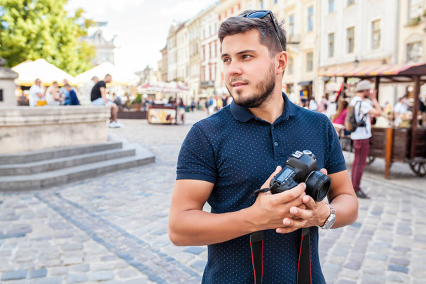 young handsome hipster man walking with photo camera on old city street, summer Europe vacation, travel, hands close up, sightseeing, taking pictures, details - Fotó, kép