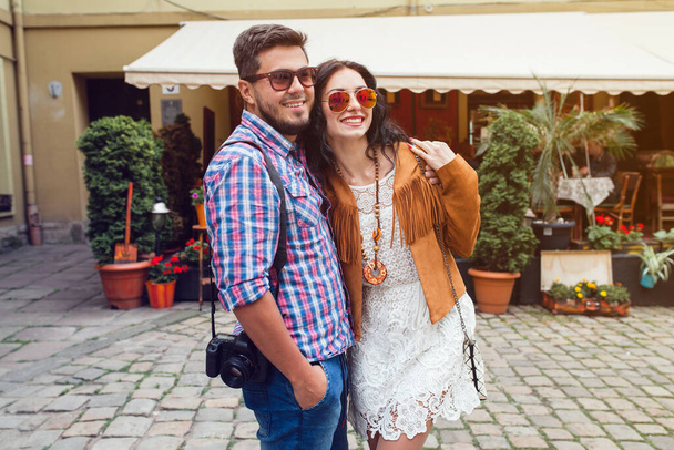 young man and woman in love traveling around europe, summer vacation, honey moon, having fun, suglasses, vintage style, smiling happy, embracing, photo camera - Fotografie, Obrázek