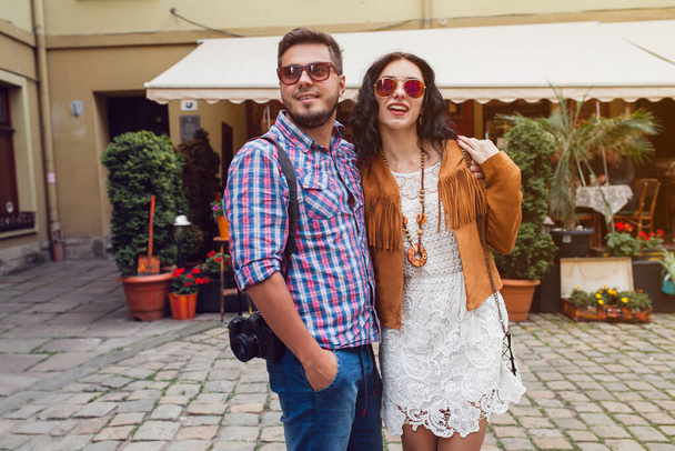 young man and woman in love traveling around europe, summer vacation, honey moon, having fun, suglasses, vintage style, smiling happy, embracing, photo camera - 写真・画像