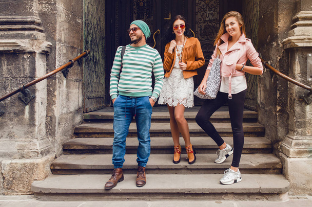 young hipster company of friends traveling, vintage style, europe vacation, sunglasses, old city center, happy positive mood, smiling, embracing, pointing finger, looking forward - Foto, imagen