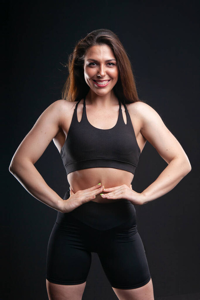 woman athlete in sportswear posing in studio on black background - Foto, afbeelding