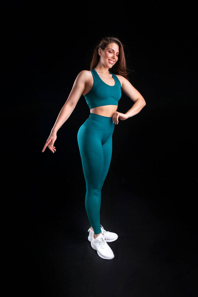 woman athlete in sportswear posing in studio on black background - Zdjęcie, obraz