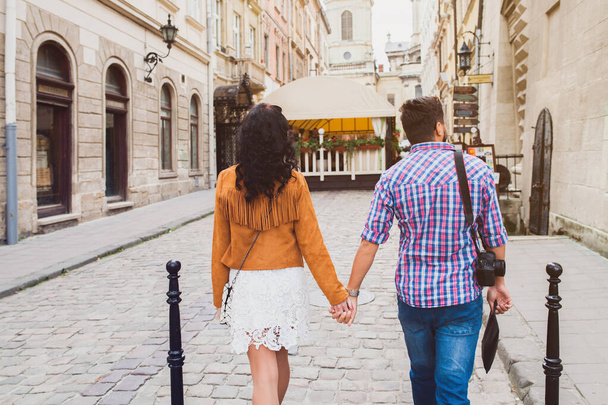 young couple in love traveling, vintage style, europe vacation, honey moon, old city center, happy positive mood, holding hands, walking together in street, view from back - Фото, изображение