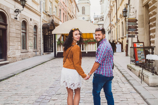 young couple in love traveling, vintage style, europe vacation, honey moon, old city center, happy positive mood, holding hands, walking together in street, view from back - Photo, Image