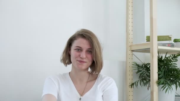 Die junge lächelnde Kaukasierin zu Hause erkennt etwas Ernstes. Stimmungswandel - Filmmaterial, Video