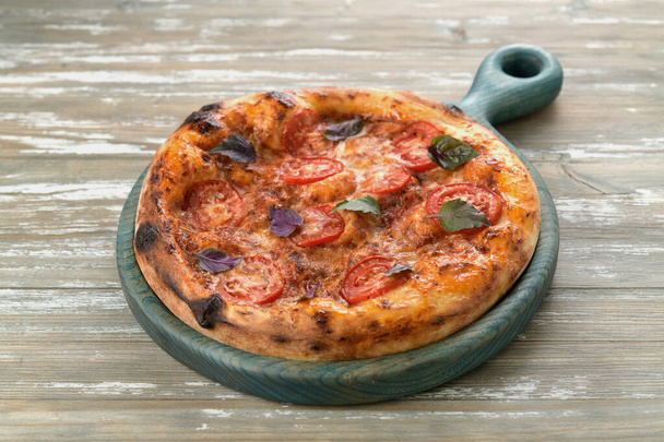 delicious pizza with tomatoes and basil on a wooden tray - Photo, Image