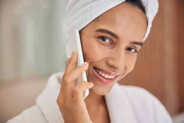 Elbűvölő fiatal nő beszél mobilon zuhanyzás után - Fotó, kép