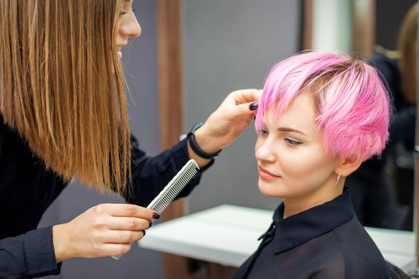 Fiatal nő kap rövid rózsaszín frizura női fodrász szépségszalonban - Fotó, kép