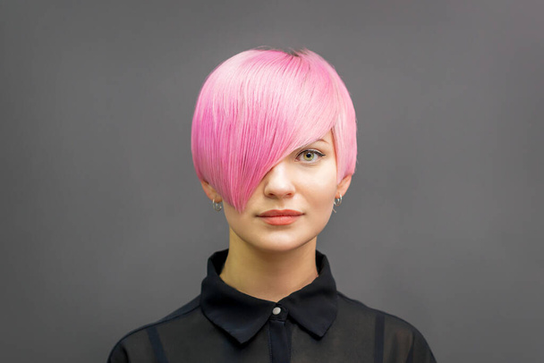 Πορτρέτο μιας όμορφης νεαρής καυκάσιας γυναίκας με κοντά φωτεινά ροζ μαλλιά. Επαγγελματική βαφή μαλλιών - Φωτογραφία, εικόνα