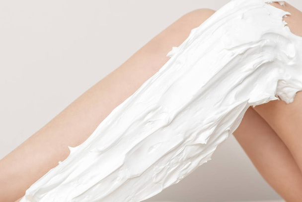 Female nice long slim bare legs with shaving foam on white background - Photo, Image