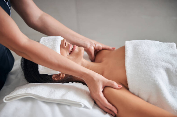 Masseur hands massaging young woman shoulders in spa salon - Фото, изображение