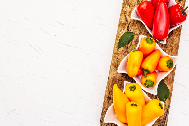Assorted ripe multi-colored baby peppers: red, orange and yellow. Fresh harvest, juicy products for healthy lifestyle. White putty background, copy space - Photo, Image