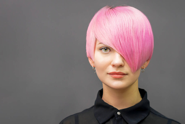 Retrato de uma bela jovem mulher caucasiana com cabelo curto rosa brilhante. Coloração de cabelo profissional - Foto, Imagem