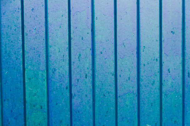 Blauer Metallprofilzaun mit einem Muster vertikaler Linien oder Streifen mit abgestufter Struktur und konvexer Textur oder Hintergrund. Makro aus nächster Nähe - Foto, Bild