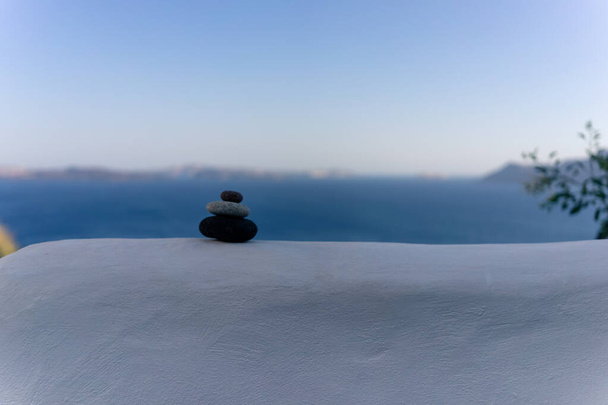 Nahaufnahme von aufeinander gestapelten Kieselsteinen in einem Gleichgewicht mit dem blauen Meer im Hintergrund - Foto, Bild