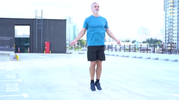 fitness, sport and exercising concept - man skipping with jump rope outdoors. - Video